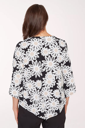 Woman wearing a black top with white floral lace pattern on a white background