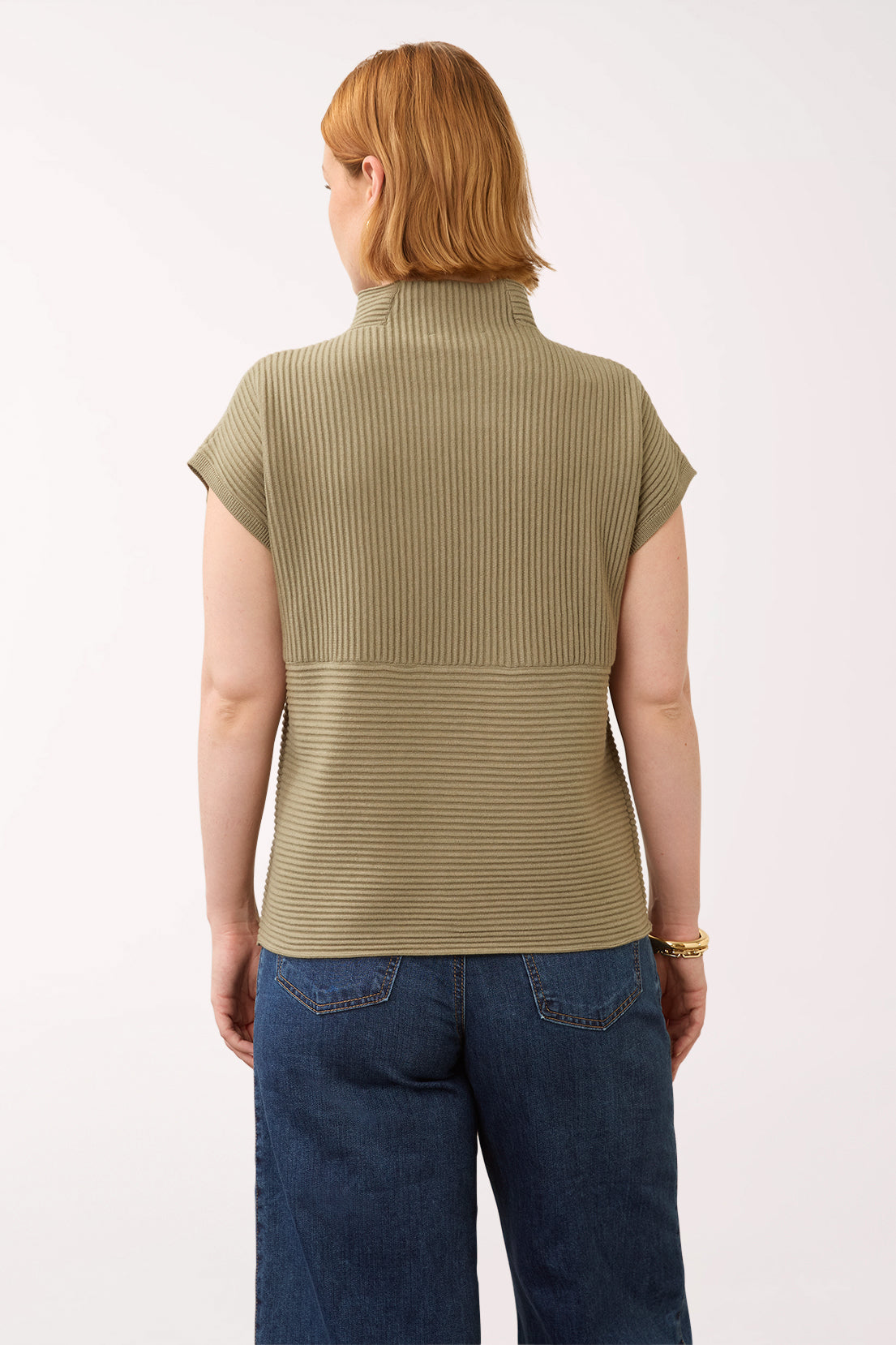 Woman wearing a olive green cap sleeve olive sweater with a mockneck
