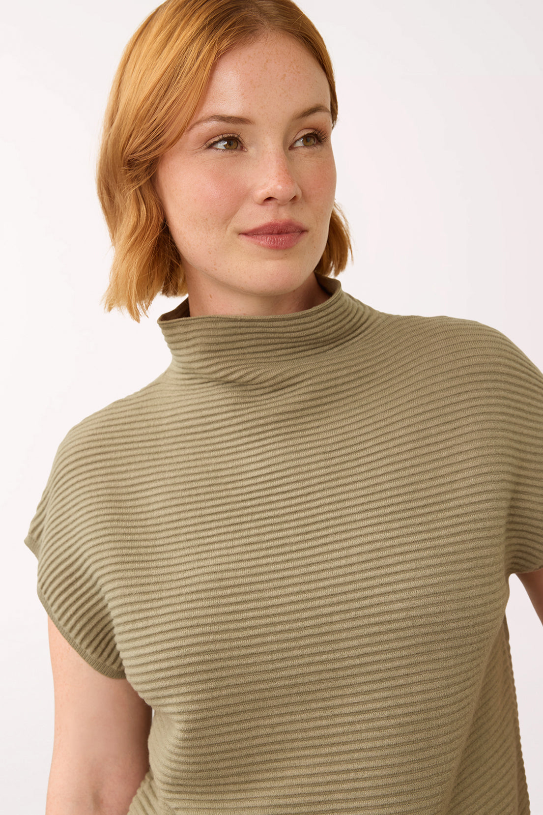 Woman wearing a olive green cap sleeve olive sweater with a mockneck