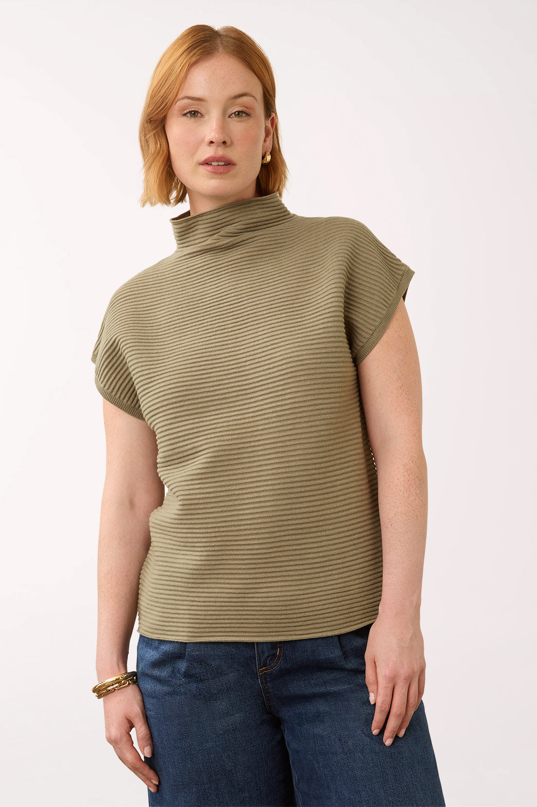 Woman wearing a olive green cap sleeve olive sweater with a mockneck