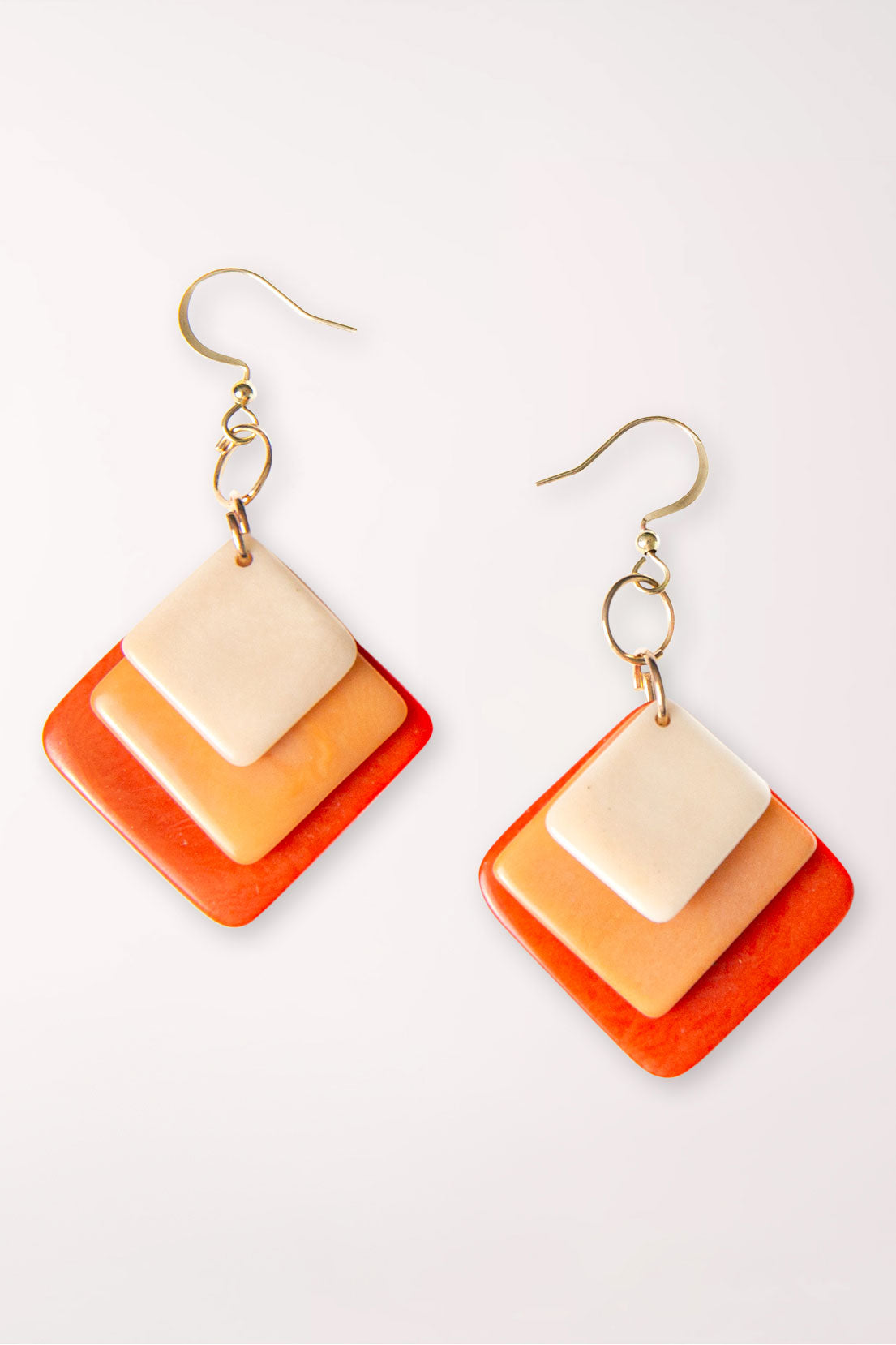 Pair of square-shaped earrings with orange and beige gradient on a white background