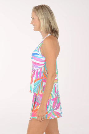 Woman wearing a colorful leaf-patterned dress on a white background. Side shot.