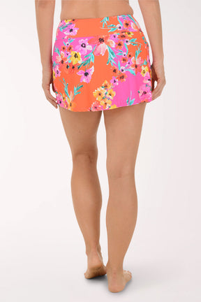 Person wearing a colorful floral skirt on a white background. Back shot.