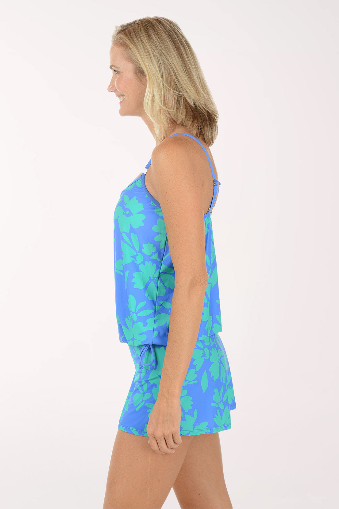 Woman wearing a blue floral dress on a white background. Side shot.