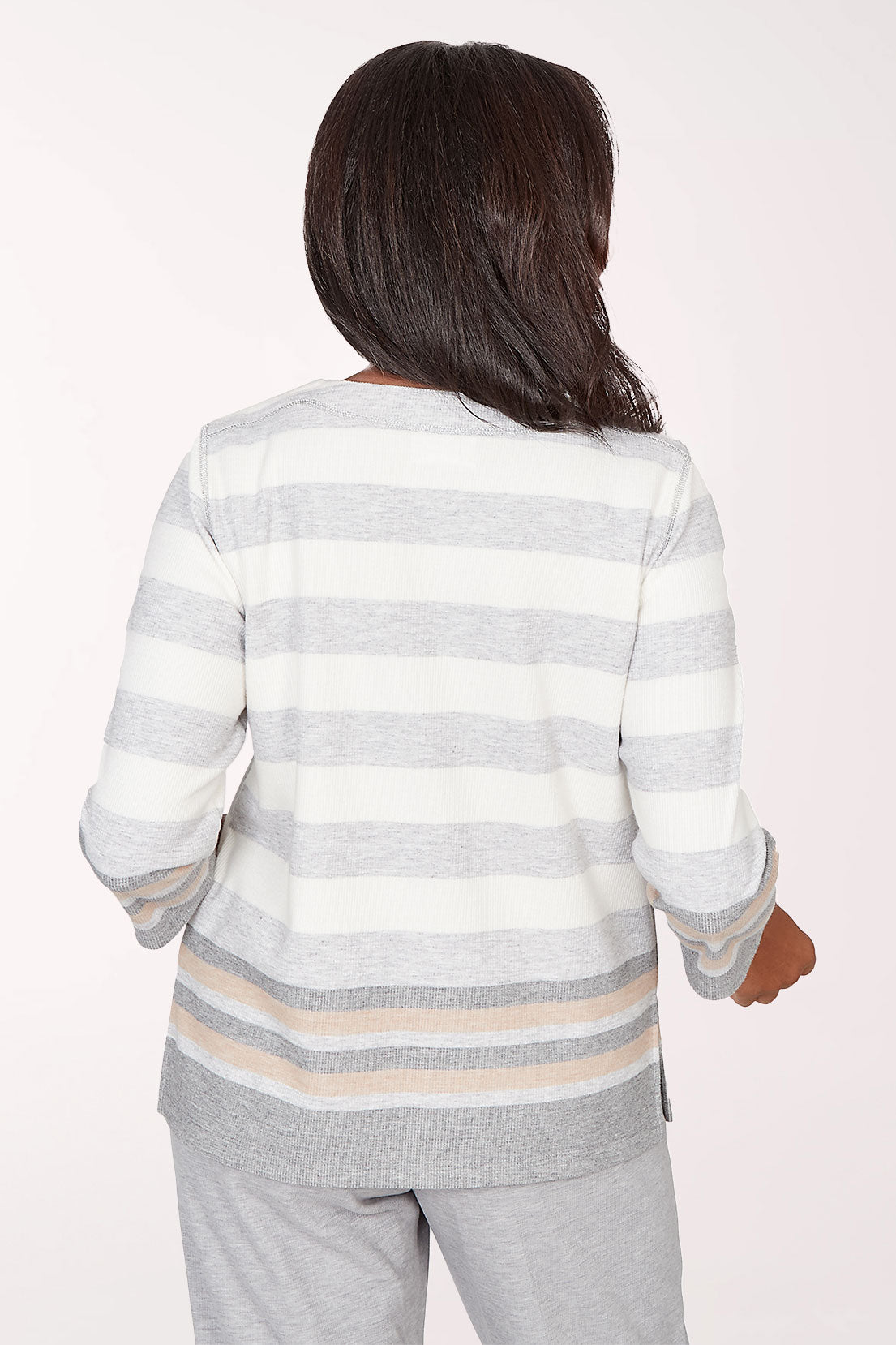 Woman wearing a gray and white striped long-sleeve top with star designs on a light pink background