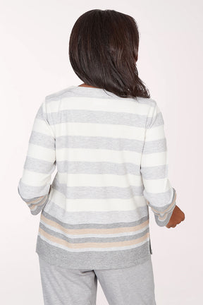 Woman wearing a gray and white striped long-sleeve top with star designs on a light pink background