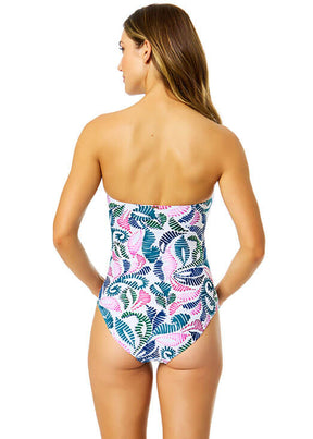 Woman wearing a strapless swimsuit with a colorful leaf pattern on a white background