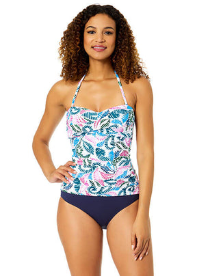 Woman wearing a colorful tropical leaf patterned tankini top and navy high-waisted bottoms on a white background