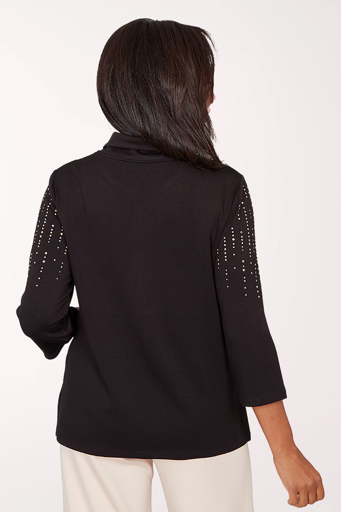 Woman wearing a black top with decorative trim on a white background