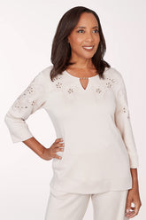Woman wearing a white blouse with floral embellishments on a white background