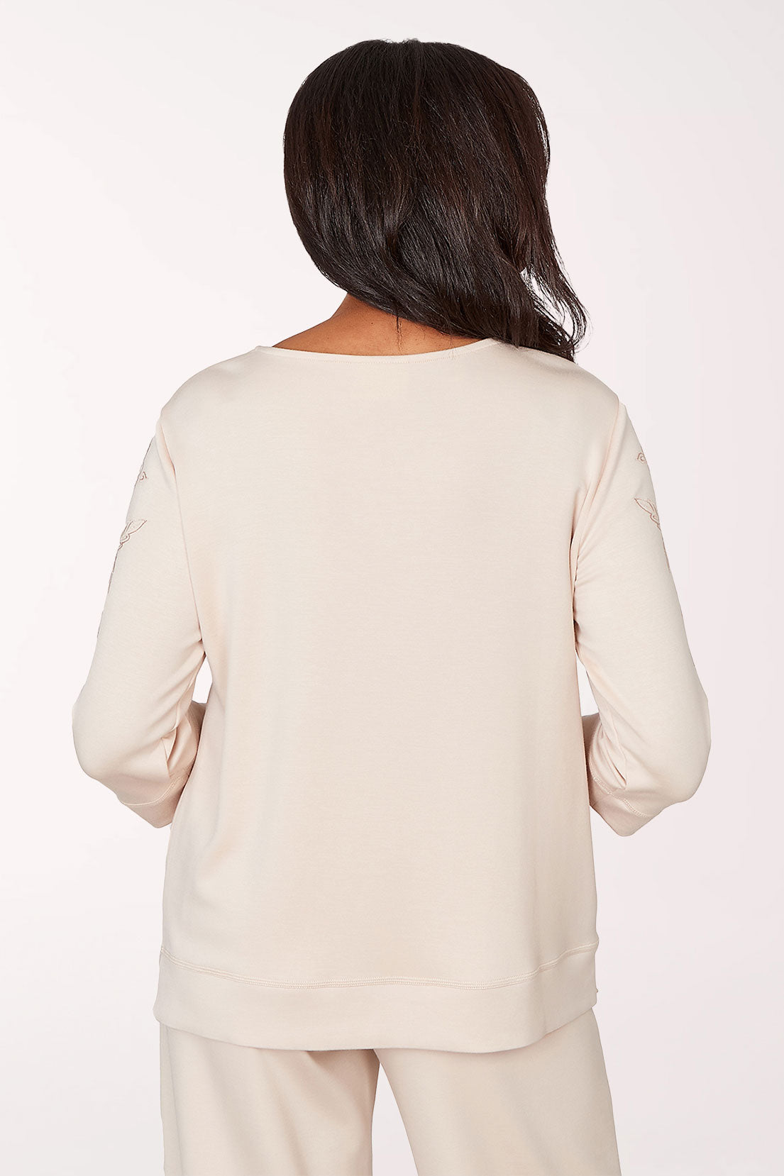 Woman wearing a white blouse with floral embellishments on a white background