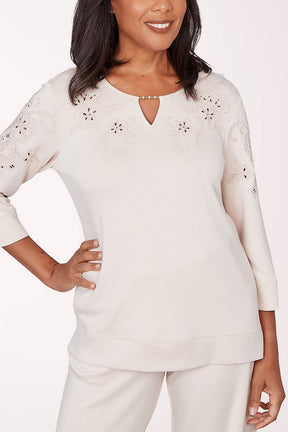 Woman wearing a white blouse with floral embellishments on a white background