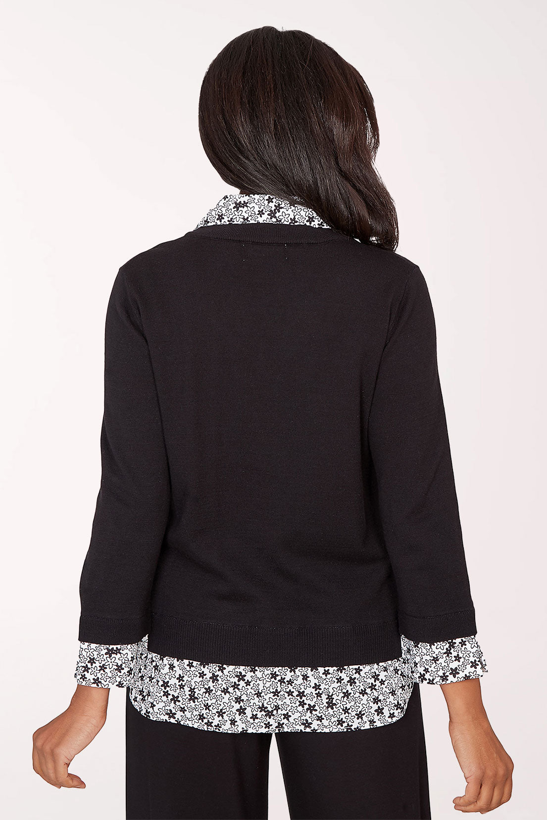 Woman wearing a black top with floral trim on a white background