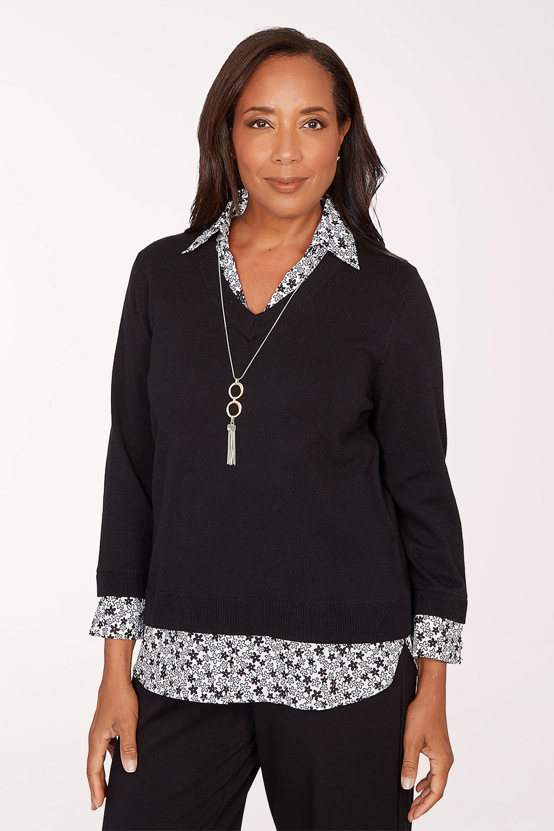 Woman wearing a black top with floral trim on a white background