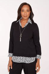 Woman wearing a black top with floral trim on a white background