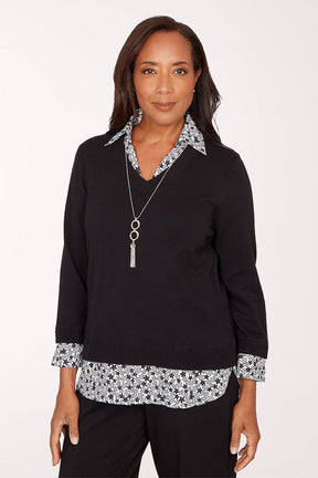 Woman wearing a black top with floral trim on a white background