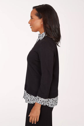 Woman wearing a black top with floral trim on a white background