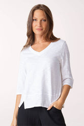 Woman wearing a white V-neck top with black pants on a white background
