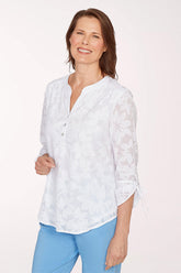 Woman wearing a white lace blouse and light blue pants on a white background
