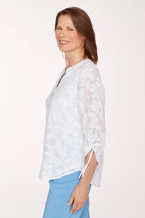 Woman wearing a white lace blouse and light blue pants on a white background