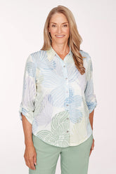 Woman wearing a patterned shirt and green pants on a white background