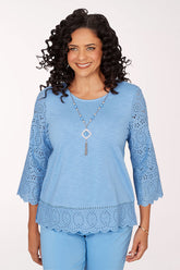 Woman wearing a light blue top with lace details on a white background
