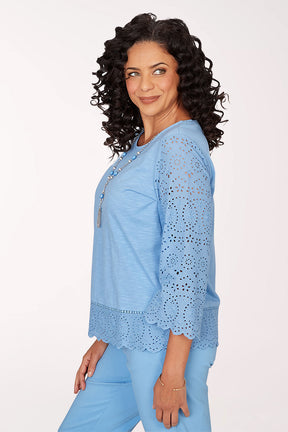 Woman wearing a light blue top with lace details on a white background