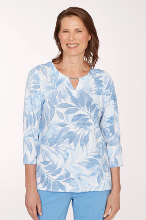 Woman wearing a blue and white leaf-patterned shirt on a white background