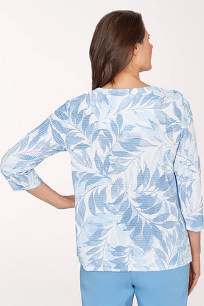 Woman wearing a blue and white leaf-patterned shirt on a white background