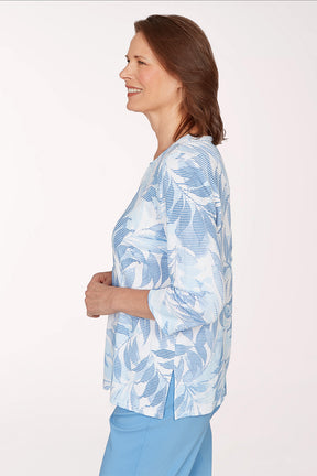 Woman wearing a blue and white leaf-patterned shirt on a white background