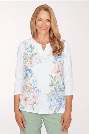 Woman wearing a white blouse with floral embroidery on a white background