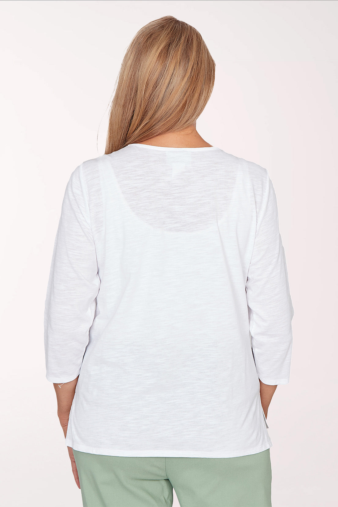 Woman wearing a white blouse with floral embroidery on a white background