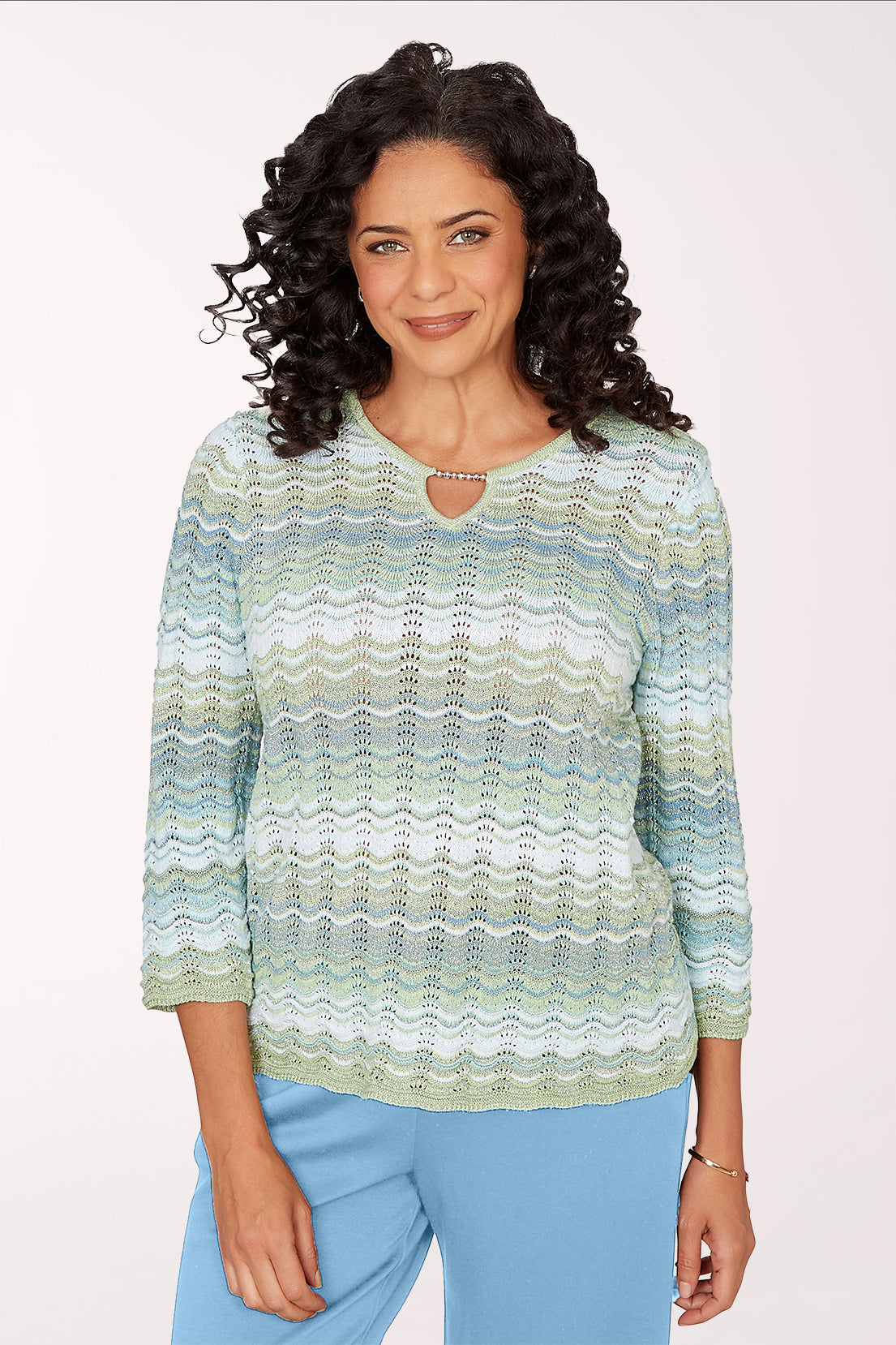 Woman wearing a patterned sweater and blue pants on a white background