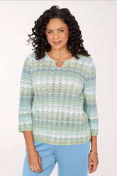 Woman wearing a patterned sweater and blue pants on a white background