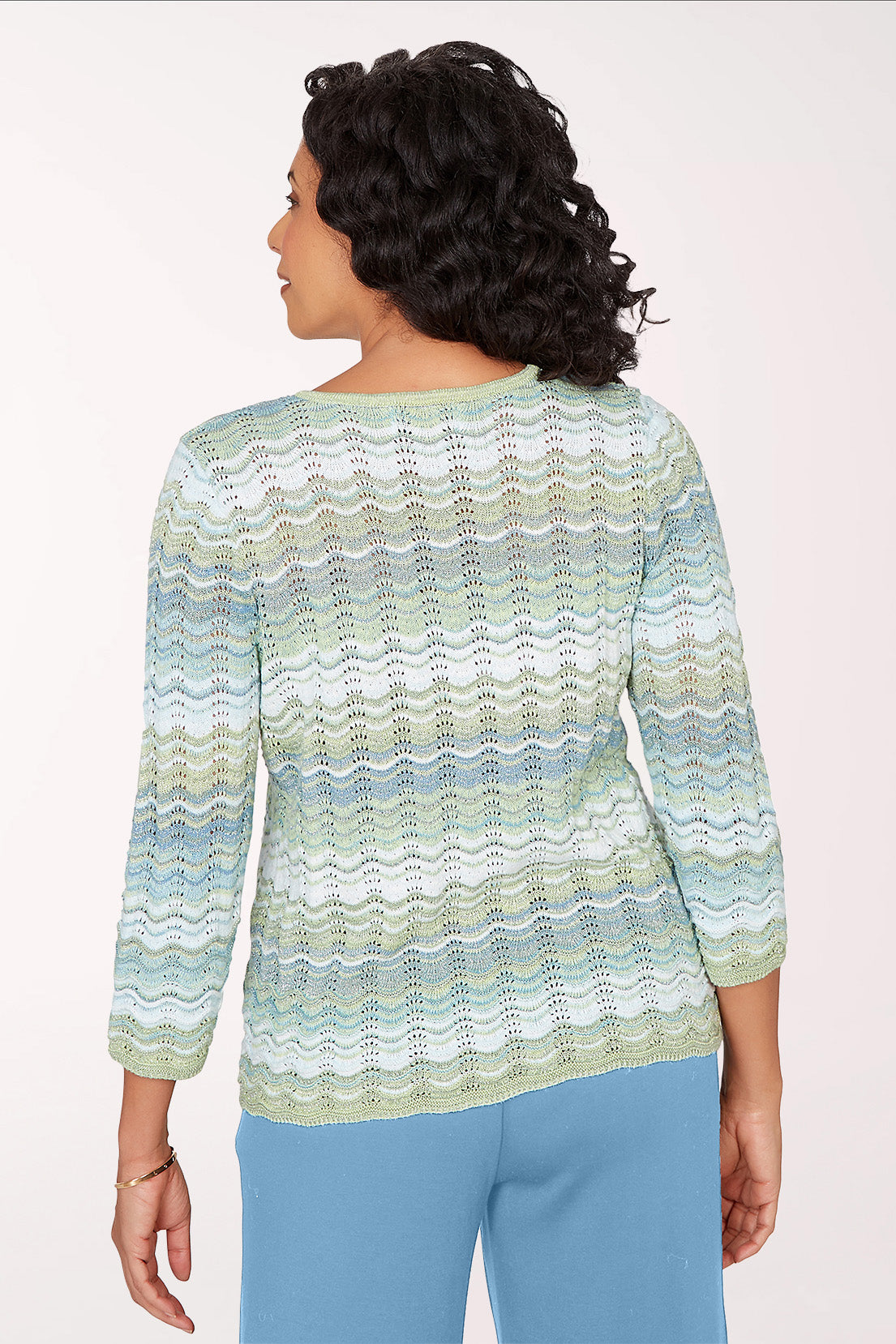 Woman wearing a patterned sweater and blue pants on a white background