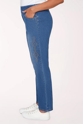 Person wearing blue jeans and white sneakers on a light pink background