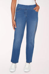 Person wearing blue jeans and white sneakers on a light pink background