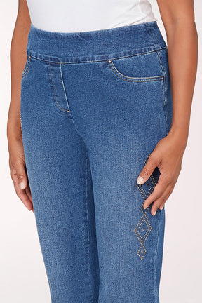 Person wearing blue jeans and white sneakers on a light pink background