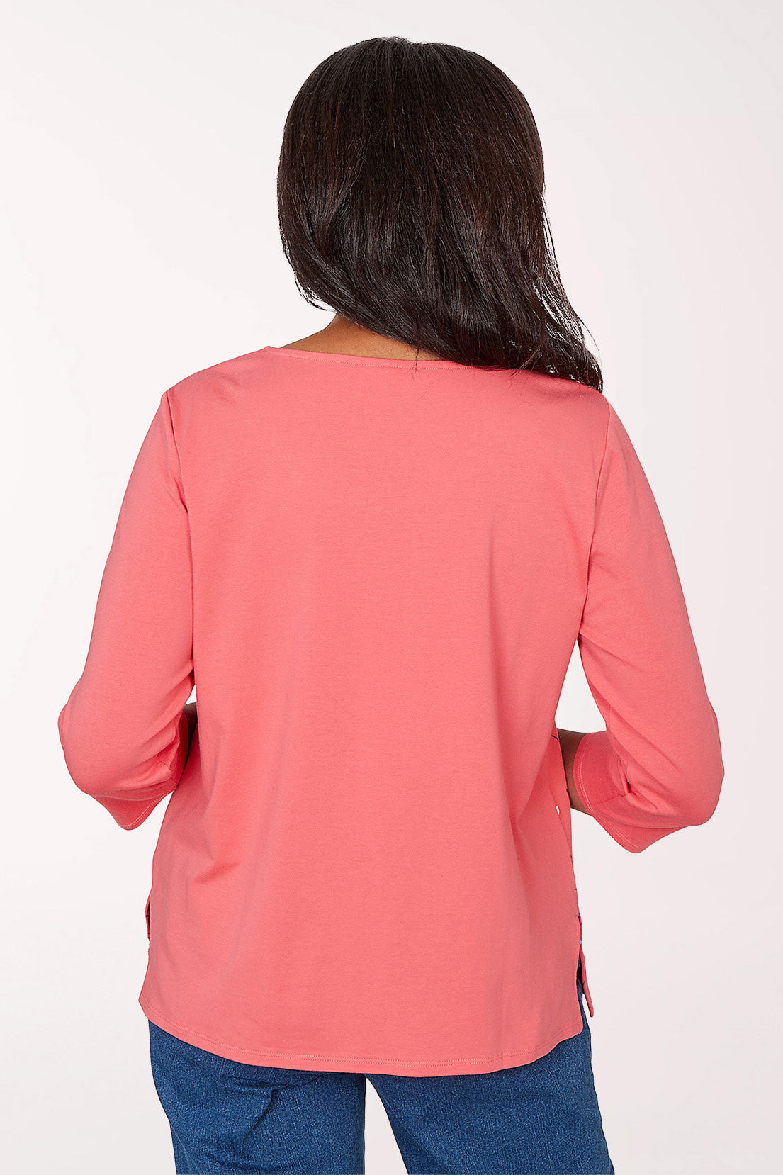 Woman wearing a pink floral blouse with blue jeans on a white background