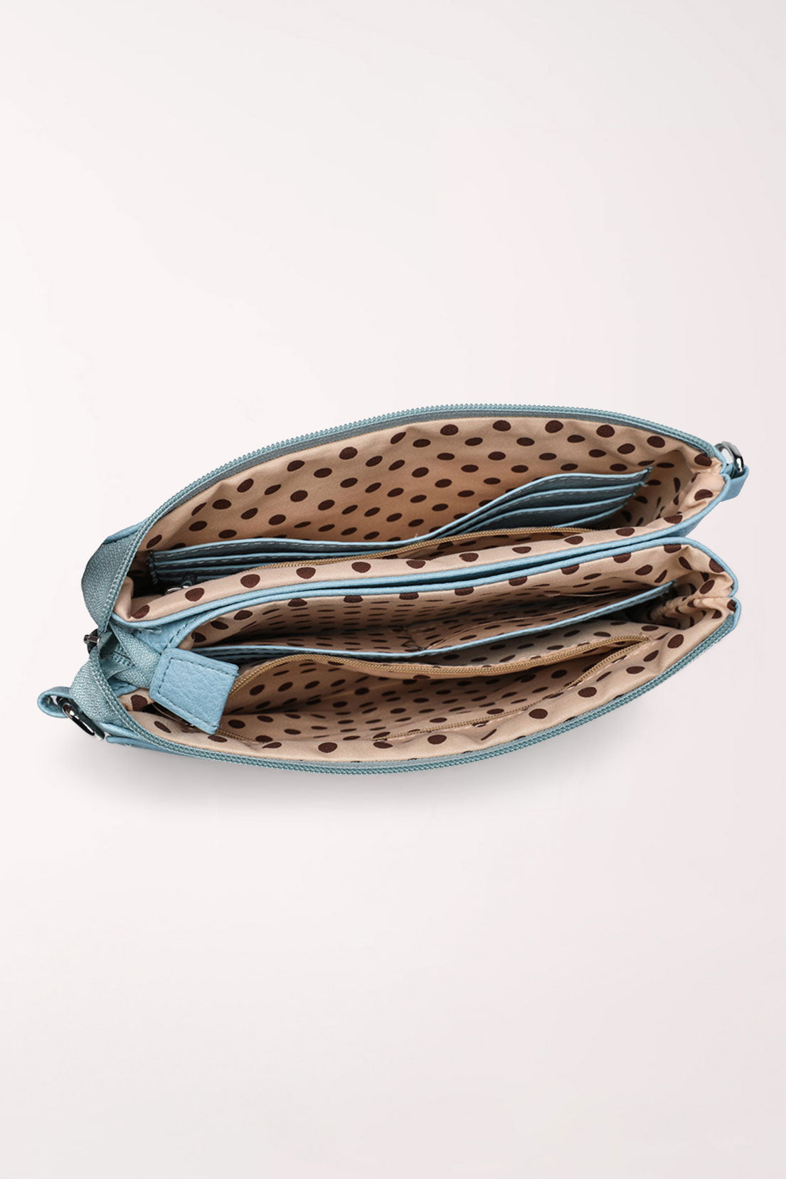 Top view of the baby blue 22 Tote Two-Sided Crossbody Bag with both zip compartments open, showing tan lining with brown polka dots and inner pockets.