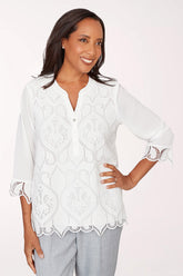 Woman wearing a white lace blouse with a plain background