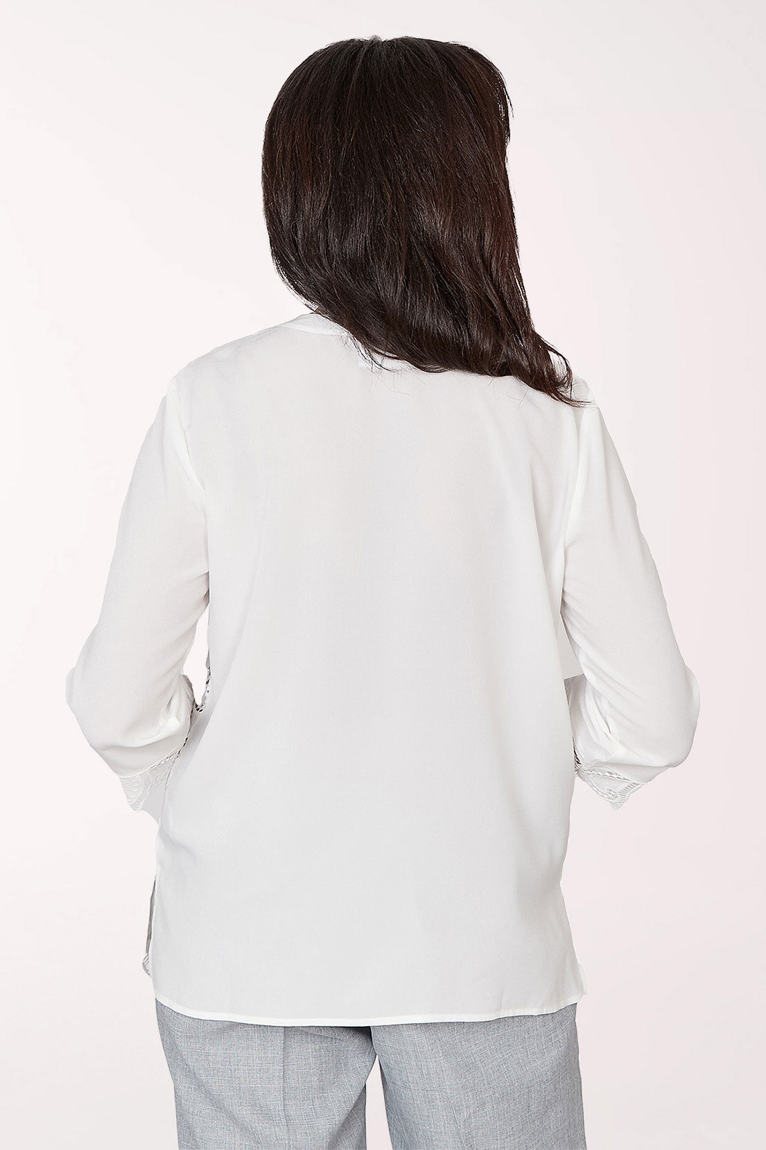 Woman wearing a white lace blouse with a plain background