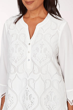 Woman wearing a white lace blouse with a plain background
