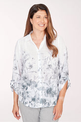 Woman wearing a light-colored floral blouse with rolled-up sleeves on a white background