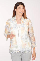 Woman wearing a floral lace kimono-style jacket over a white top on a white background