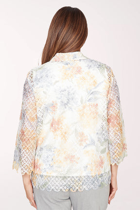 Woman wearing a floral lace kimono-style jacket over a white top on a white background