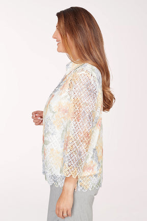 Woman wearing a floral lace kimono-style jacket over a white top on a white background