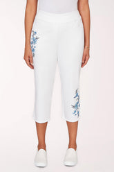 White capri pants with floral embroidery on a white background