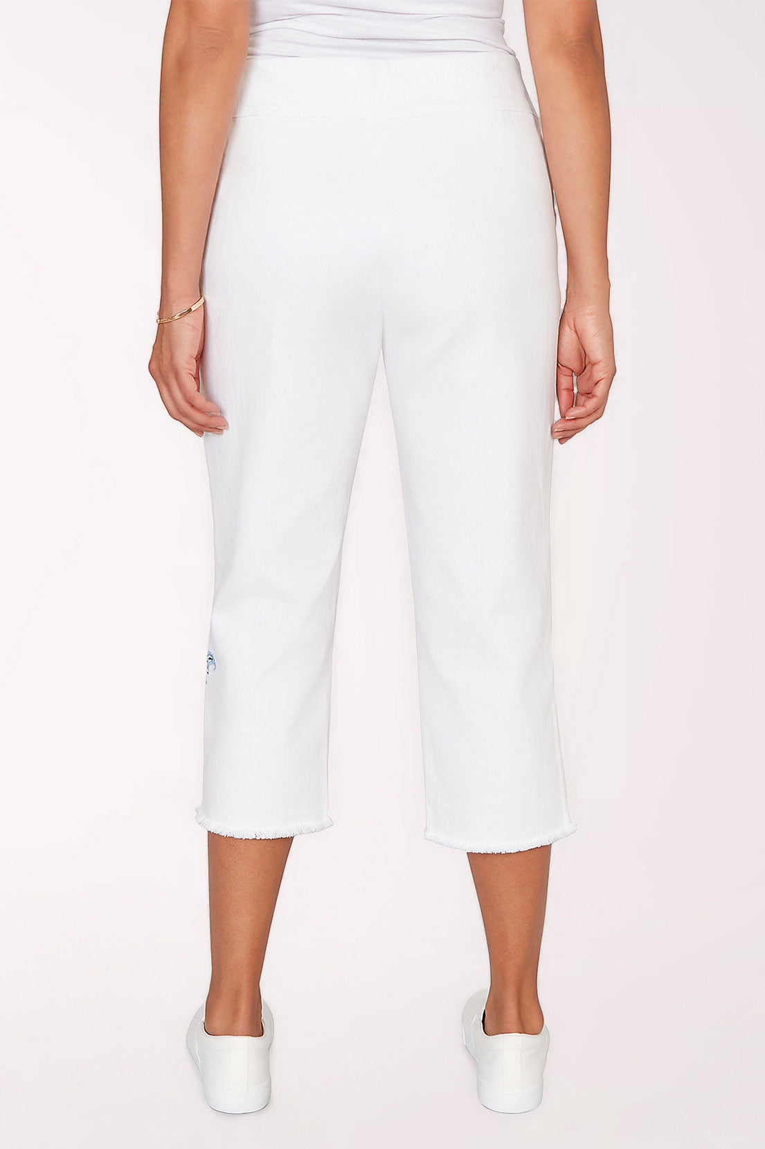 White capri pants with floral embroidery on a white background