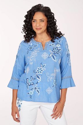 Woman wearing a blue embroidered blouse against a white background